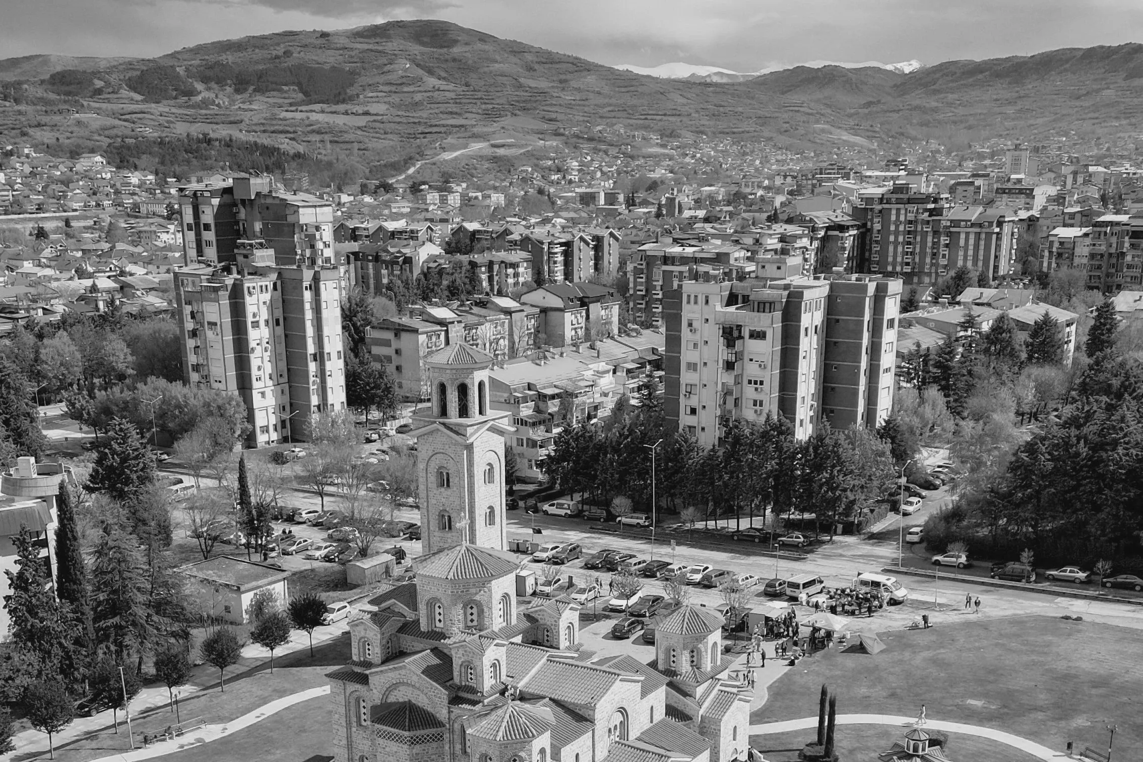 Kavadarci from the air: the Church of Saint Petka and its bell tower in front, apartment blocks and roofs behind, and terraced hills above the town.